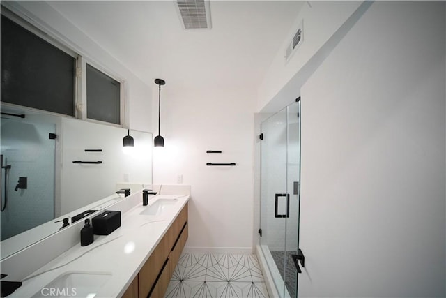 full bath with double vanity, a shower stall, visible vents, and a sink