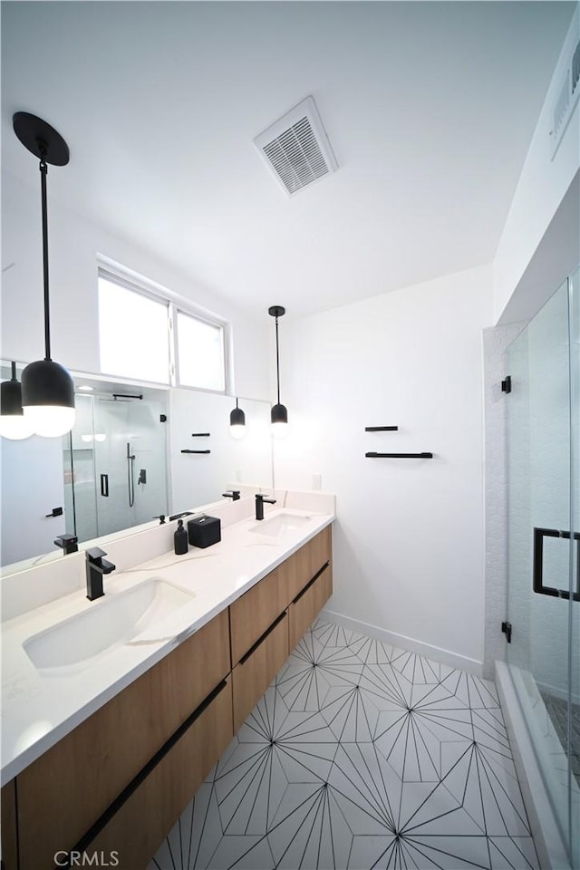 bathroom with double vanity, a stall shower, visible vents, and a sink