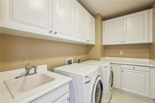 laundry room with separate washer and dryer, cabinet space, and a sink