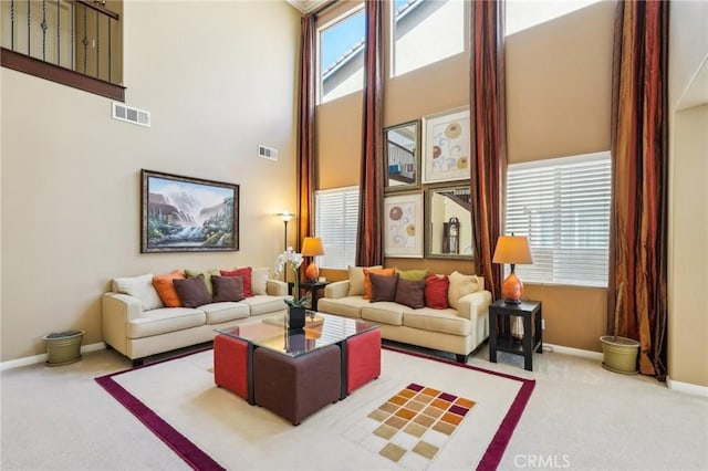 living room with visible vents, baseboards, a towering ceiling, and carpet floors