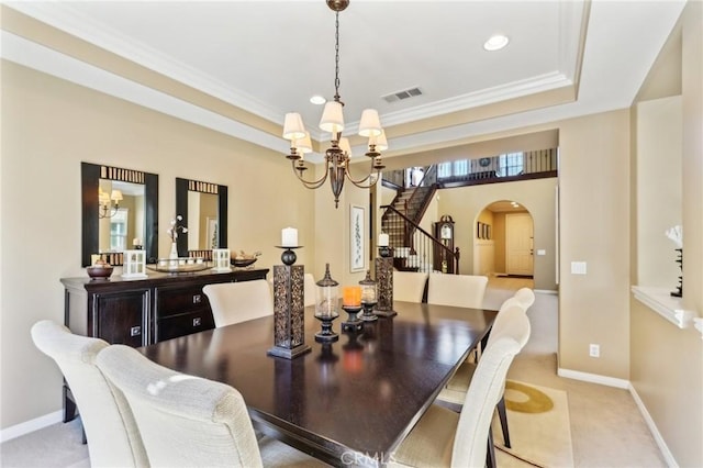 dining space with an inviting chandelier, a tray ceiling, arched walkways, and visible vents