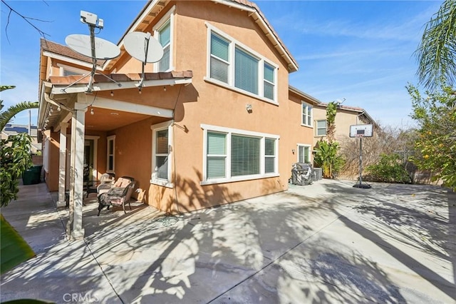 rear view of house featuring stucco siding and a patio area