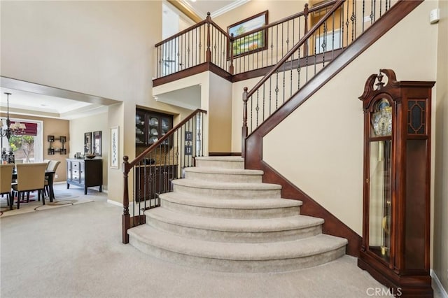 stairs featuring a high ceiling, baseboards, crown molding, and carpet