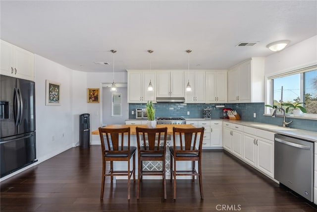 kitchen with under cabinet range hood, a sink, black fridge with ice dispenser, visible vents, and stainless steel dishwasher