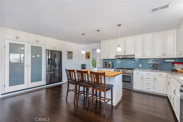 kitchen featuring appliances with stainless steel finishes, backsplash, visible vents, and under cabinet range hood