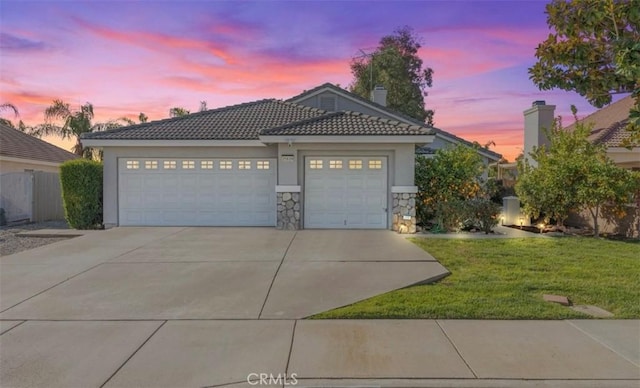 view of front of home with a tile roof, stucco siding, concrete driveway, a lawn, and an attached garage