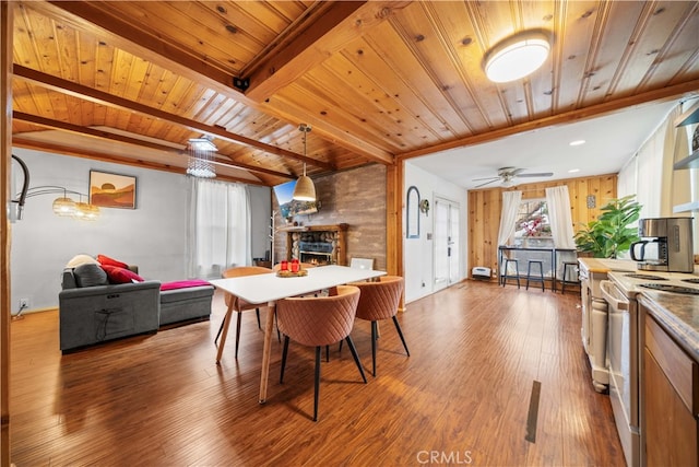 dining room with a ceiling fan, wood ceiling, wood finished floors, a fireplace, and beam ceiling