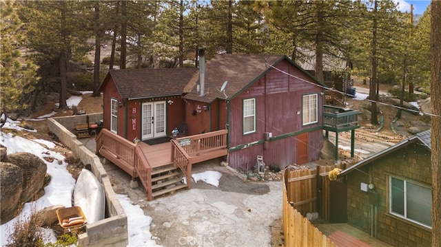 view of front of property with a deck, french doors, and a shingled roof