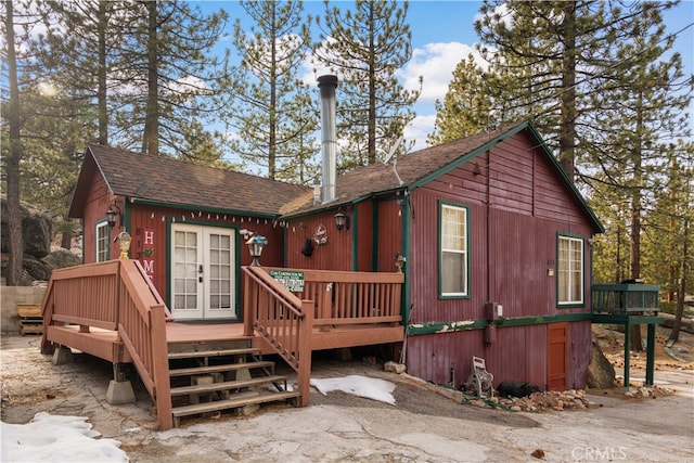 rear view of house featuring a shingled roof, french doors, and a wooden deck