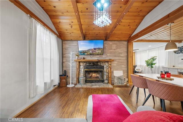 living room with lofted ceiling with beams, wooden ceiling, wood finished floors, and a stone fireplace