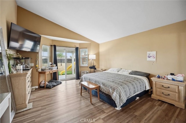 bedroom with vaulted ceiling, wood finished floors, and access to exterior