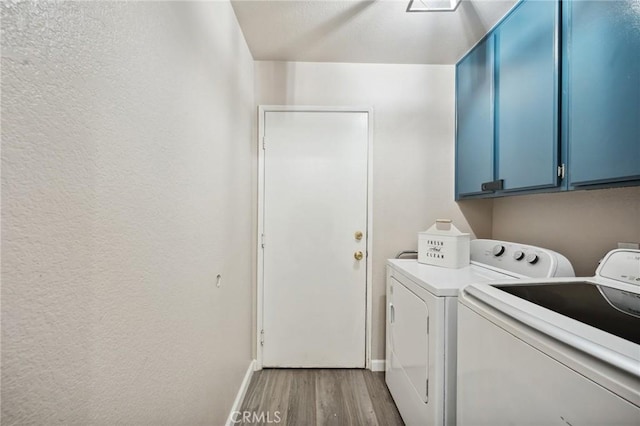 laundry area with separate washer and dryer, light wood-style flooring, cabinet space, and baseboards