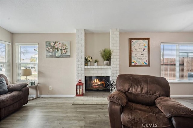 living area with a fireplace, baseboards, and wood finished floors