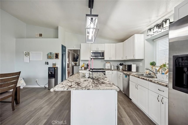 kitchen featuring lofted ceiling, a kitchen island with sink, appliances with stainless steel finishes, and visible vents