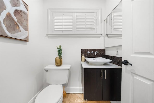 bathroom with backsplash, toilet, vanity, tile patterned flooring, and baseboards