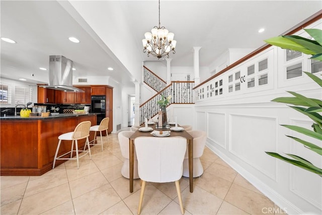 dining room featuring ornate columns, a decorative wall, crown molding, and light tile patterned flooring