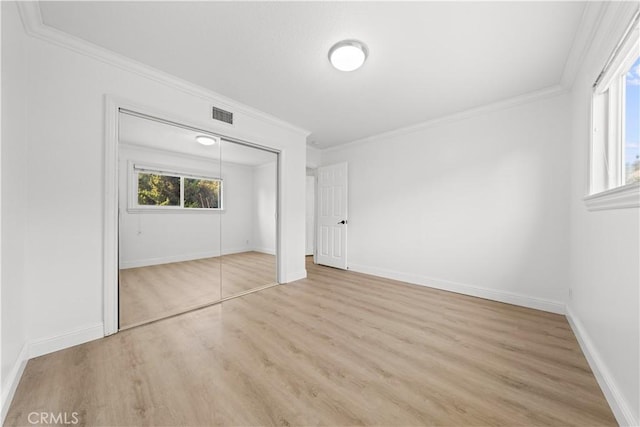 unfurnished bedroom featuring a closet, visible vents, crown molding, and wood finished floors