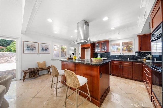 kitchen featuring island exhaust hood, light tile patterned floors, tasteful backsplash, ornamental molding, and a kitchen island