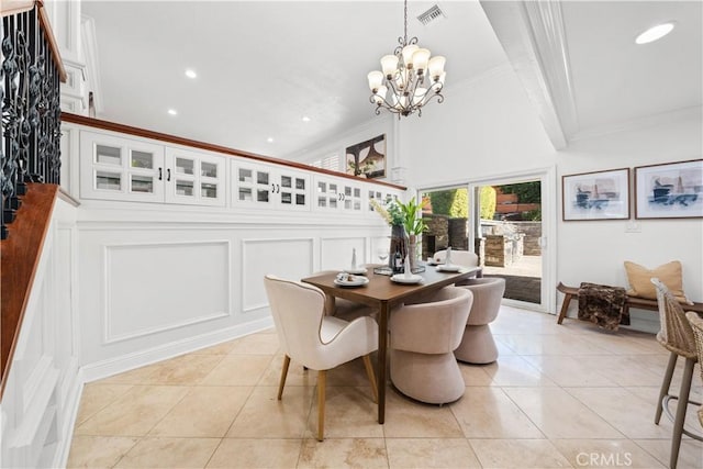 dining room featuring visible vents, crown molding, a chandelier, a decorative wall, and light tile patterned flooring