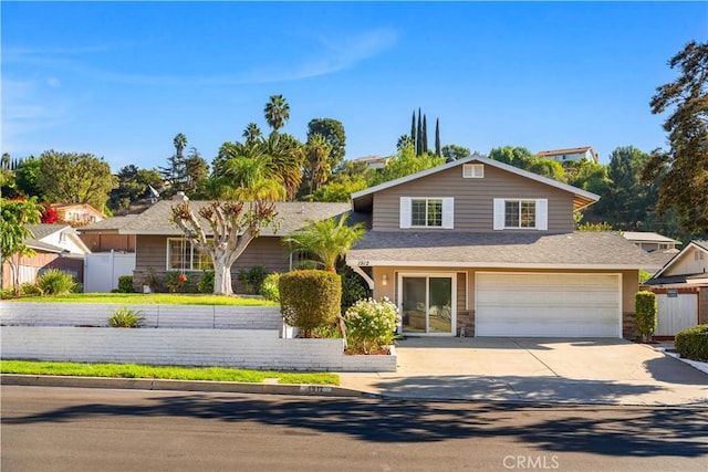 view of front of home with a garage, concrete driveway, and fence