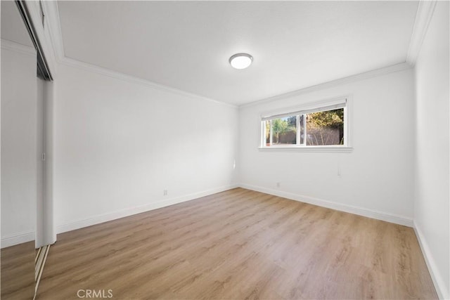 spare room with crown molding, baseboards, and wood finished floors