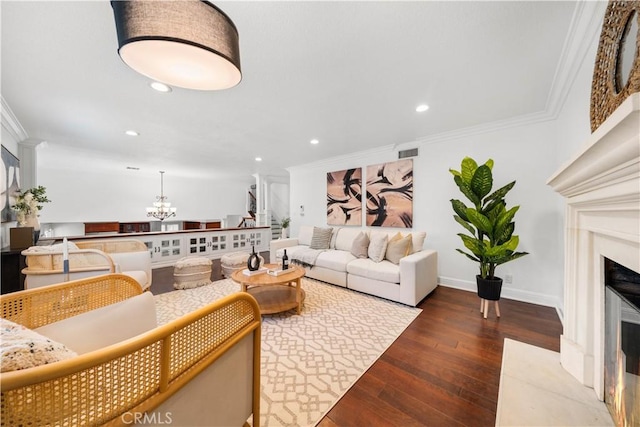 living room featuring crown molding, visible vents, an inviting chandelier, a high end fireplace, and hardwood / wood-style flooring