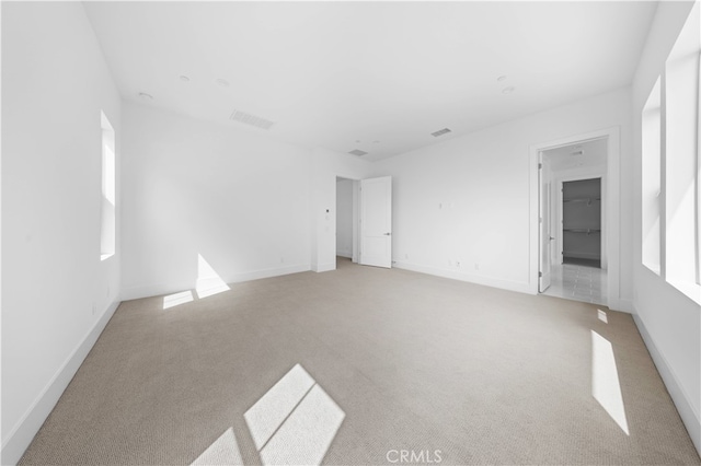 spare room featuring light carpet, visible vents, and baseboards