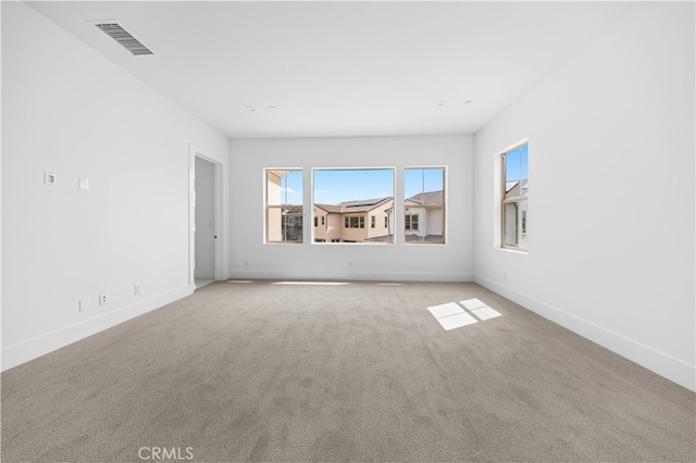 spare room featuring light carpet, visible vents, and baseboards