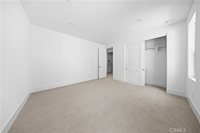 unfurnished bedroom featuring a closet, light colored carpet, and baseboards