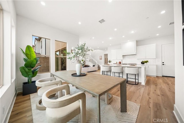 dining room featuring baseboards, light wood-type flooring, visible vents, and recessed lighting