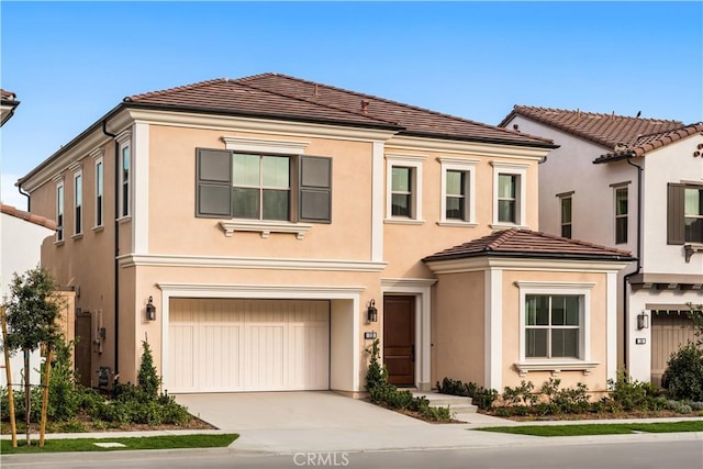 view of front facade with driveway, a tiled roof, an attached garage, and stucco siding