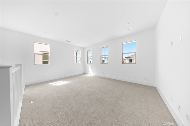 empty room with light carpet, visible vents, and baseboards