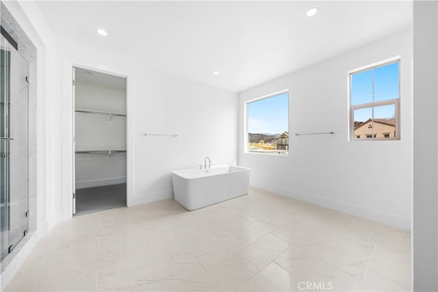 bathroom featuring a freestanding tub, a shower stall, a walk in closet, and recessed lighting