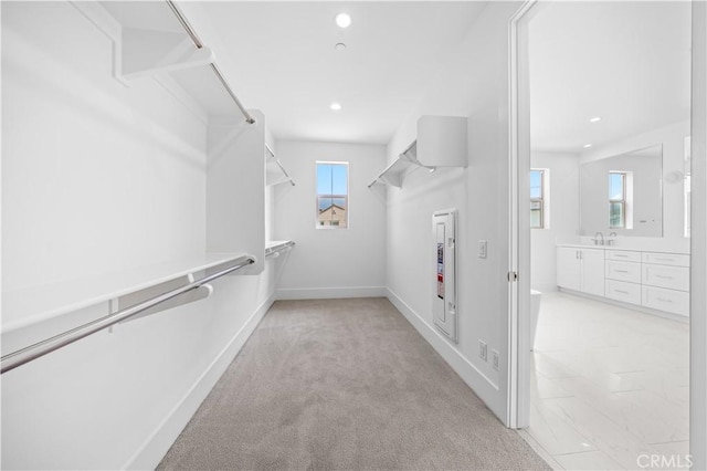 spacious closet with light carpet and a sink