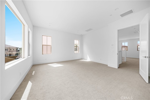 empty room featuring light carpet, visible vents, and baseboards