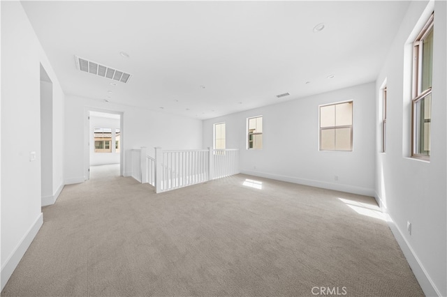 spare room with baseboards, visible vents, and light colored carpet