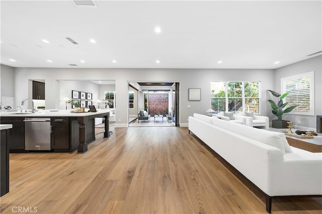 living room featuring light wood-type flooring, baseboards, visible vents, and recessed lighting