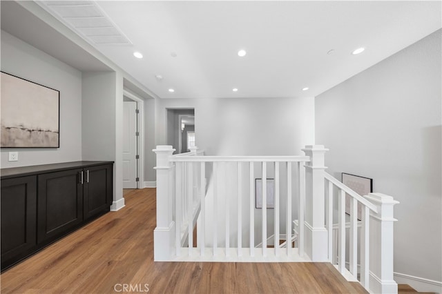 hallway with recessed lighting, light wood-style flooring, baseboards, and an upstairs landing