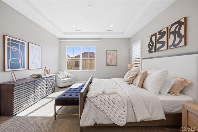 bedroom featuring a tray ceiling, multiple windows, and visible vents