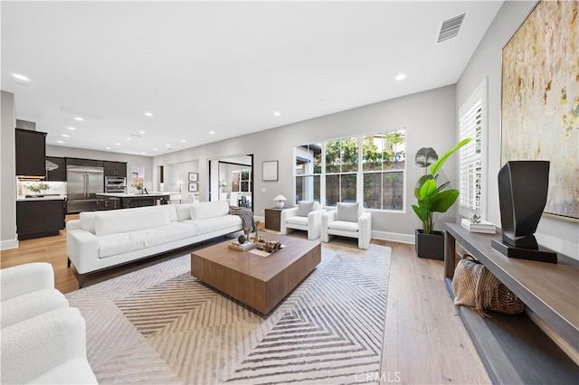 living room featuring baseboards, recessed lighting, visible vents, and light wood-style floors