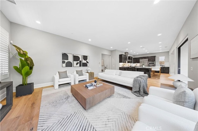 living area featuring recessed lighting, light wood-style flooring, and baseboards