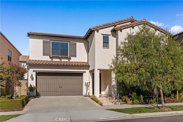 mediterranean / spanish house featuring a garage, driveway, a tiled roof, and stucco siding