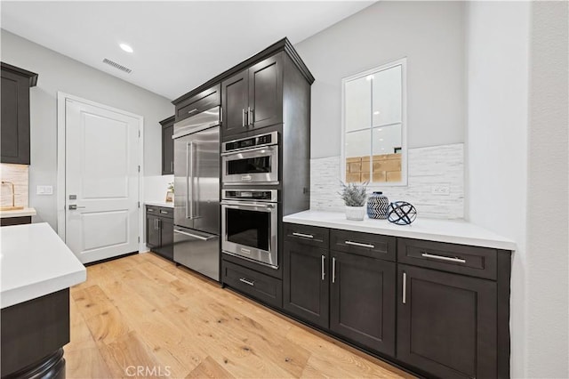 kitchen featuring visible vents, decorative backsplash, stainless steel appliances, light countertops, and light wood-type flooring