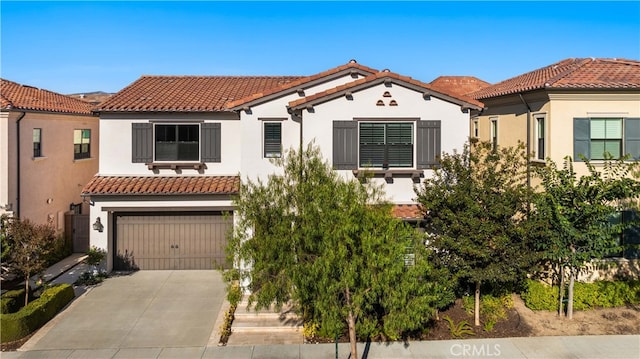 mediterranean / spanish-style house featuring a tile roof, driveway, and stucco siding