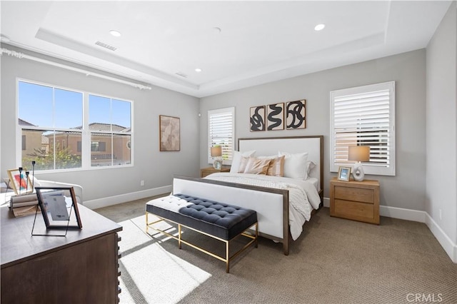 bedroom with light carpet, baseboards, visible vents, and a raised ceiling