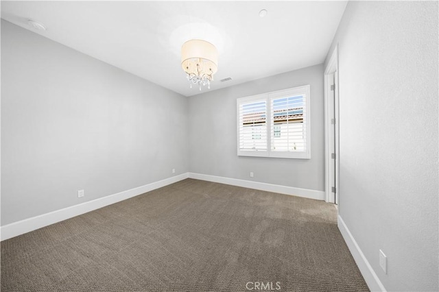 unfurnished room featuring visible vents, dark carpet, baseboards, and an inviting chandelier