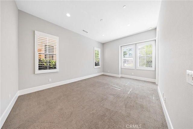 spare room featuring recessed lighting, carpet flooring, visible vents, and baseboards