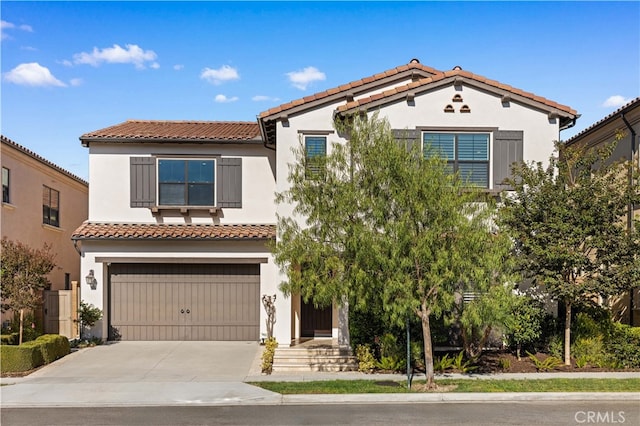 mediterranean / spanish-style home featuring driveway, a tiled roof, an attached garage, and stucco siding