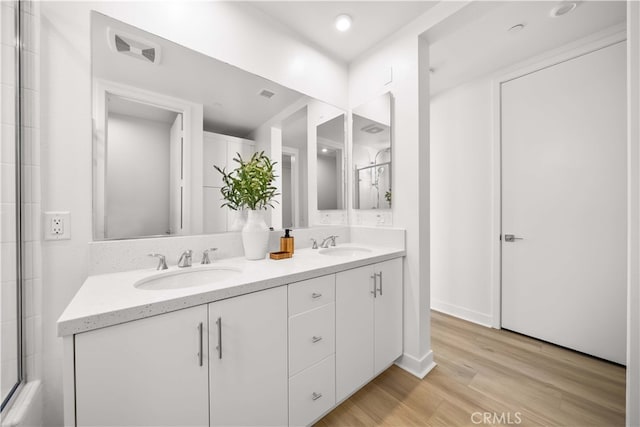 bathroom featuring double vanity, wood finished floors, a sink, and visible vents