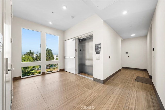 empty room with elevator, baseboards, and recessed lighting